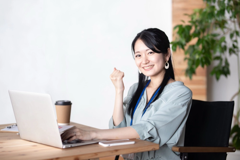 パソコンの前でガッツポーズをする女性
